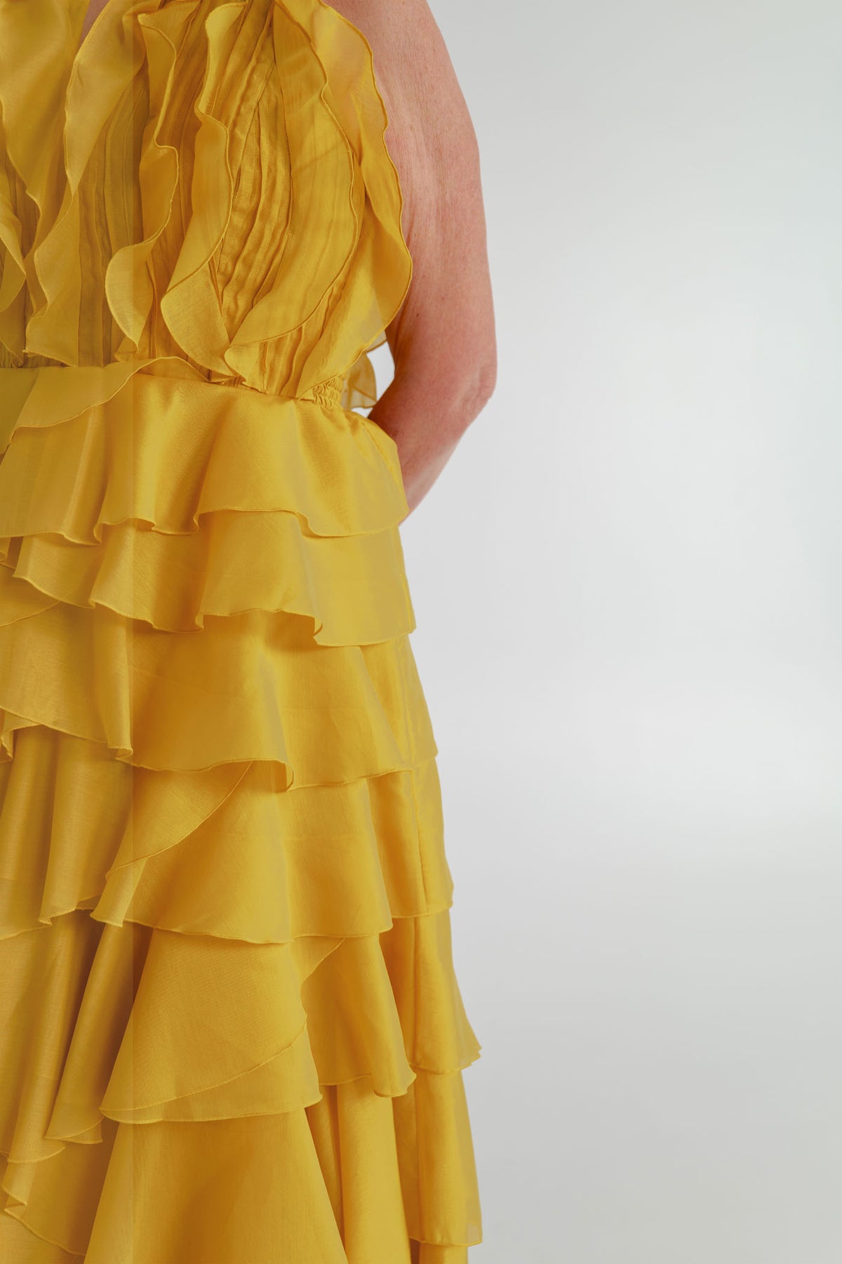 Close-up of the Aje Cleo golden chartreuse gown showing layered ruffle detailing across the bodice and skirt.