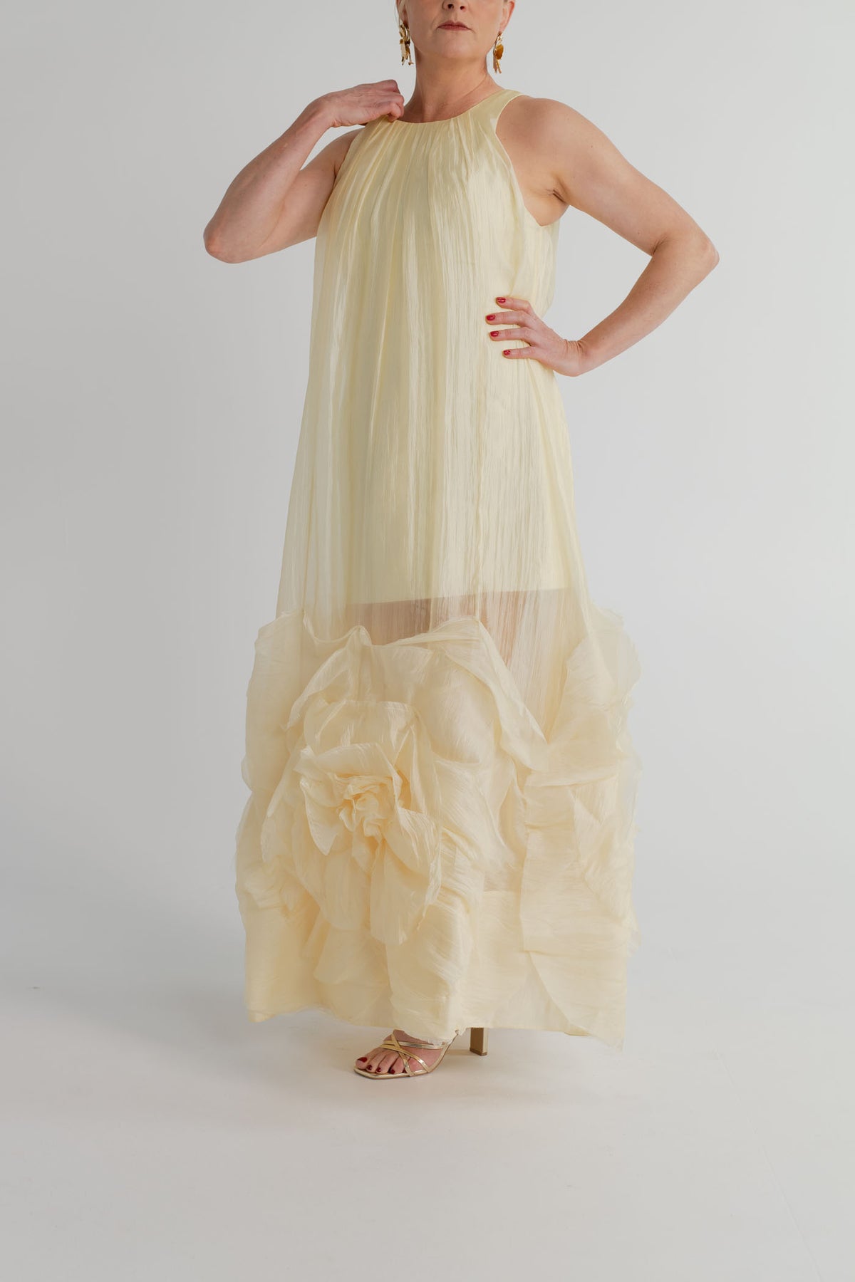 Aje Ecliptica pastel yellow sleeveless gown with high neckline, fluid shift silhouette and statement rosette hem.