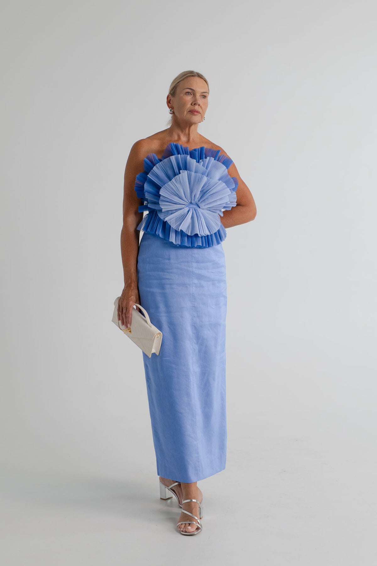 Aje Kira blue strapless midi dress with layered pleated bodice, styled with the JW Pei Celeste cream woven top handle bag.