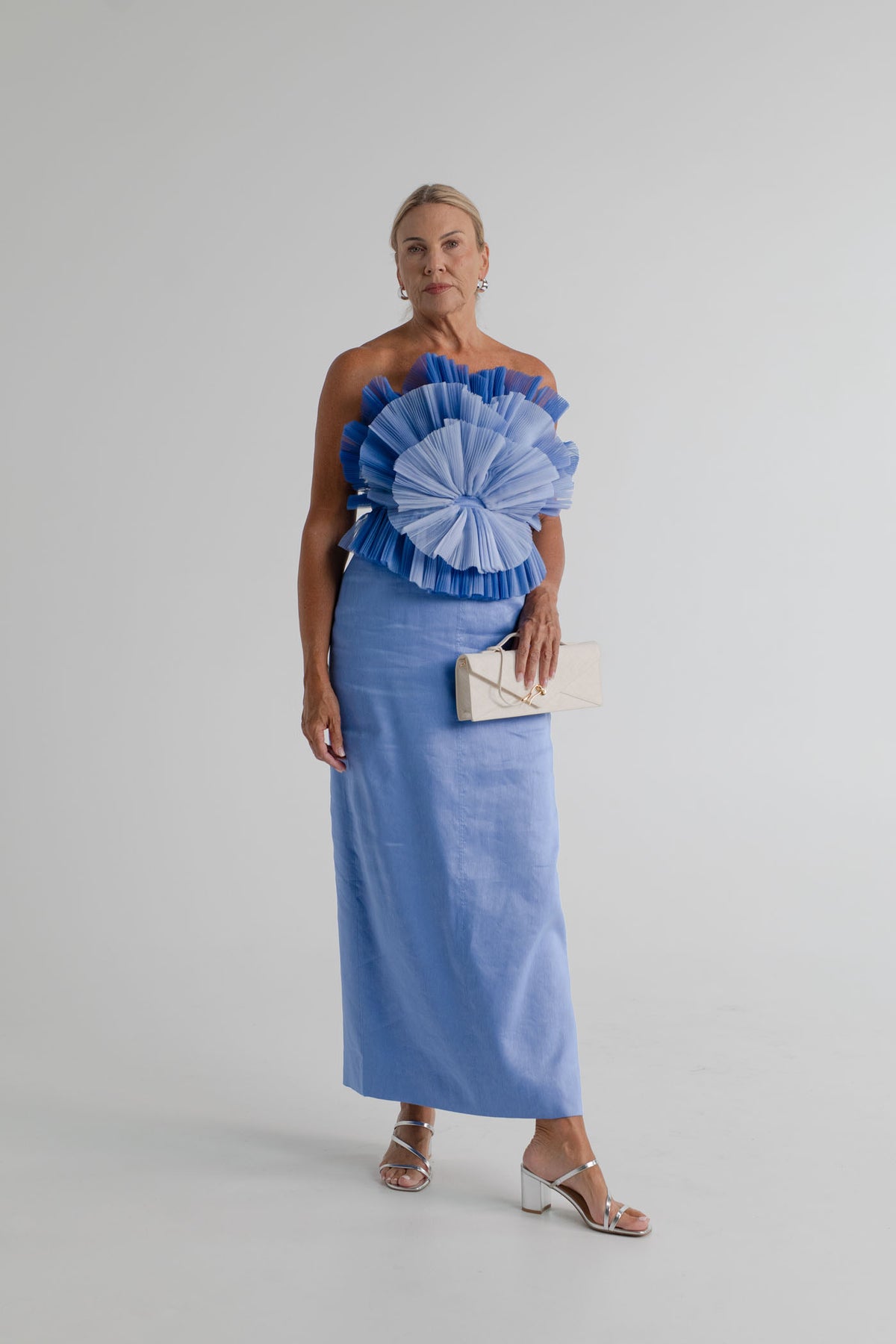 Aje Kira blue strapless midi dress with sculptural pleated frills, styled with the JW Pei Celeste cream woven top handle bag.