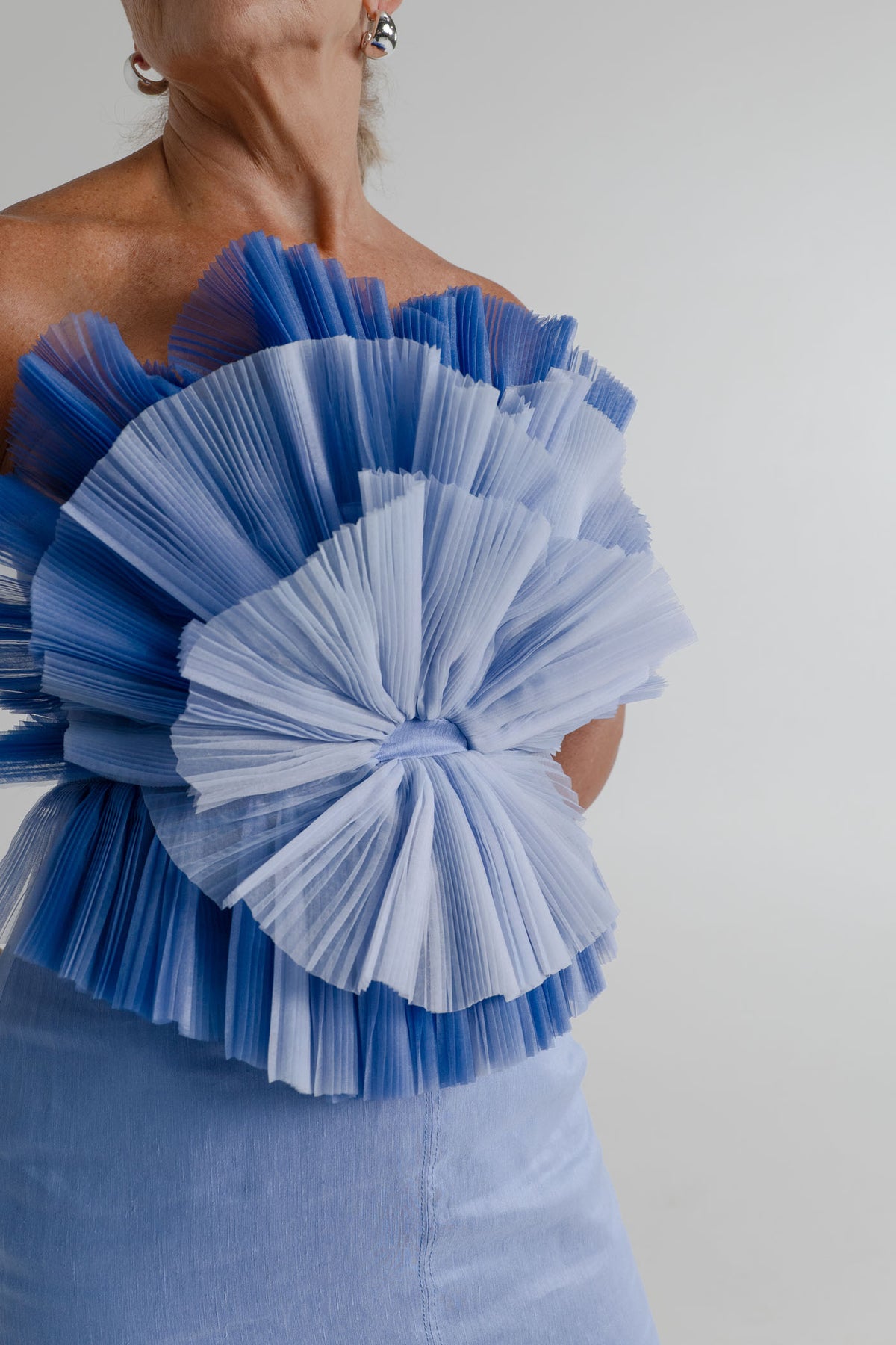 Close-up of the Aje Kira blue strapless bodice with layered sculptural pleated frills in contrasting blue tones.