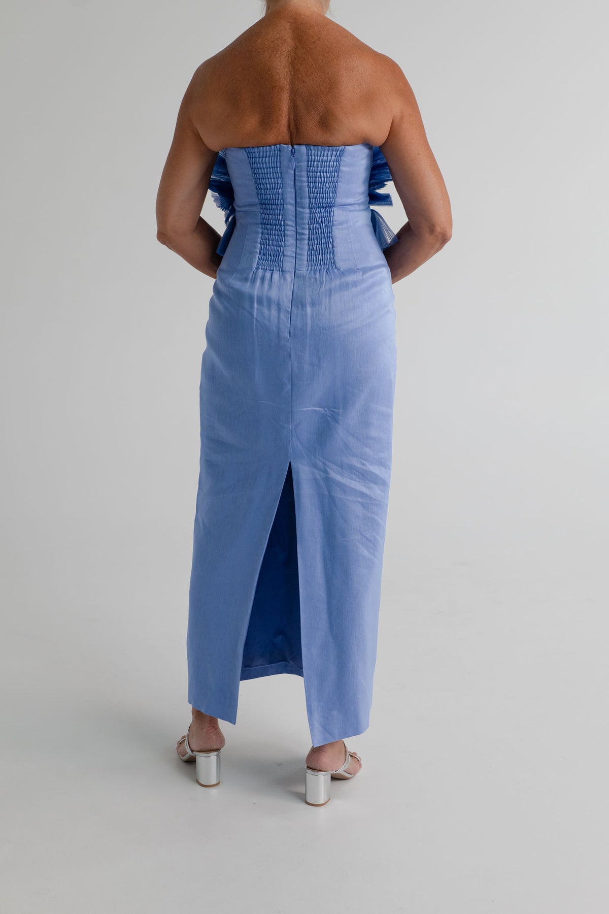 Back view of the Aje Kira blue strapless midi dress showing the structured bodice, gathered back panels and centre-back skirt split.