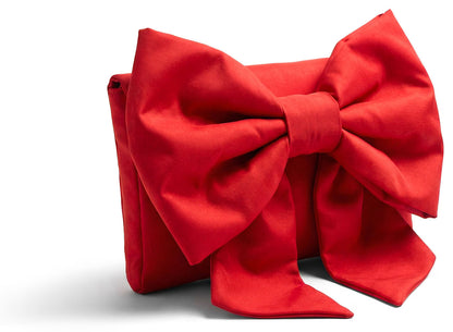 Side view of Concept à Trois red bow clutch bag showing the structured clutch shape and oversized satin bow. 
