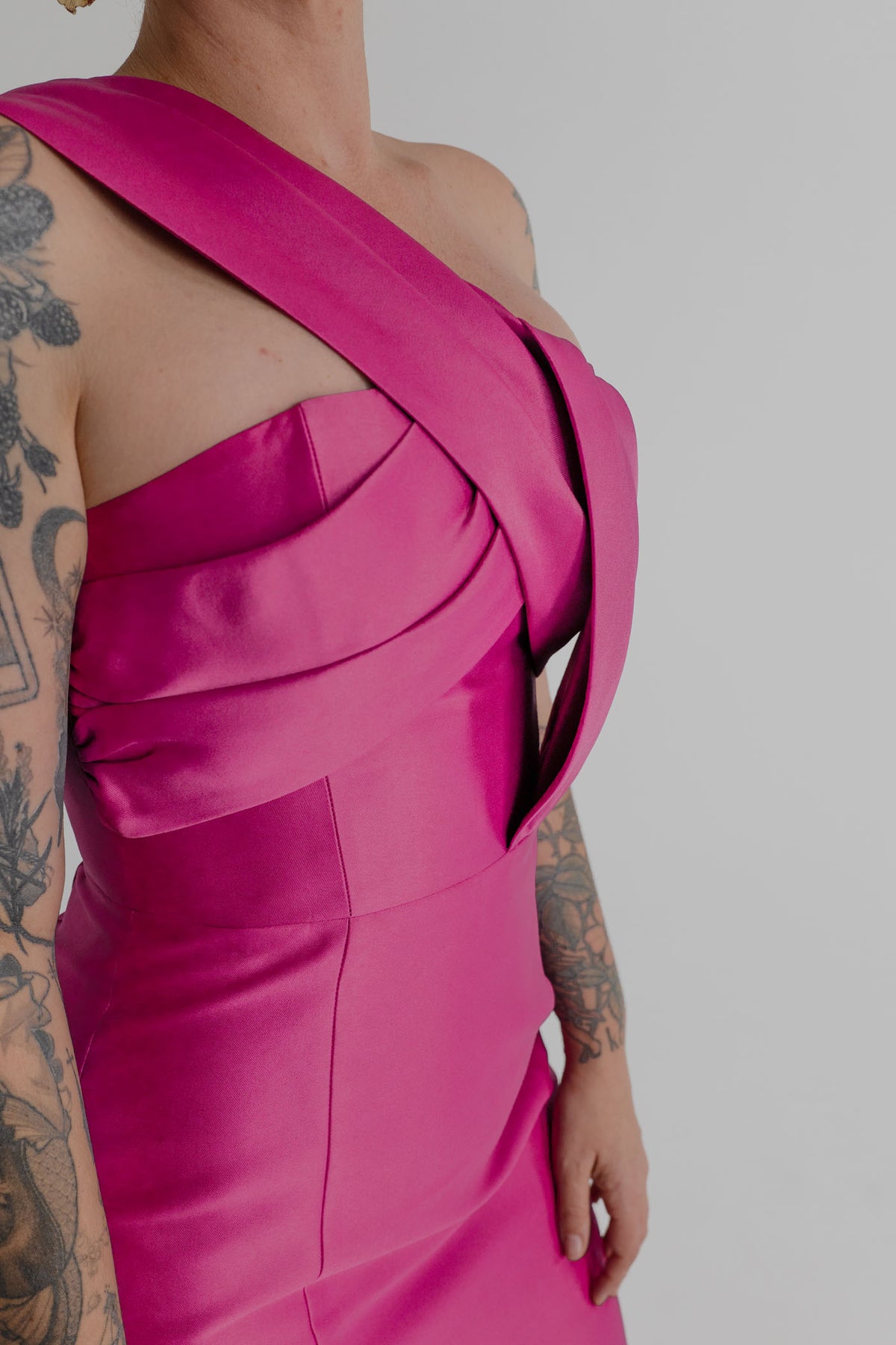Close-up of the Eliya the Label Renata magenta dress showing the sculptural one-shoulder neckline and layered folded bodice panels.
