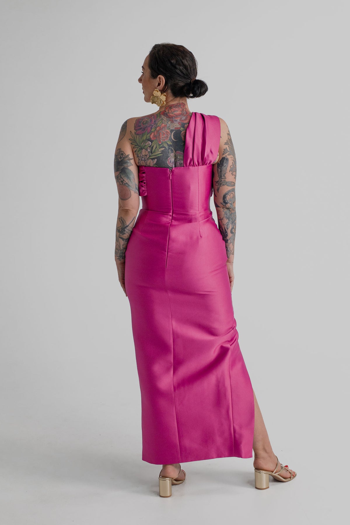 Back view of the Eliya the Label Renata magenta one-shoulder midi dress showing the fitted silhouette, asymmetric shoulder strap and centre-back zip.
