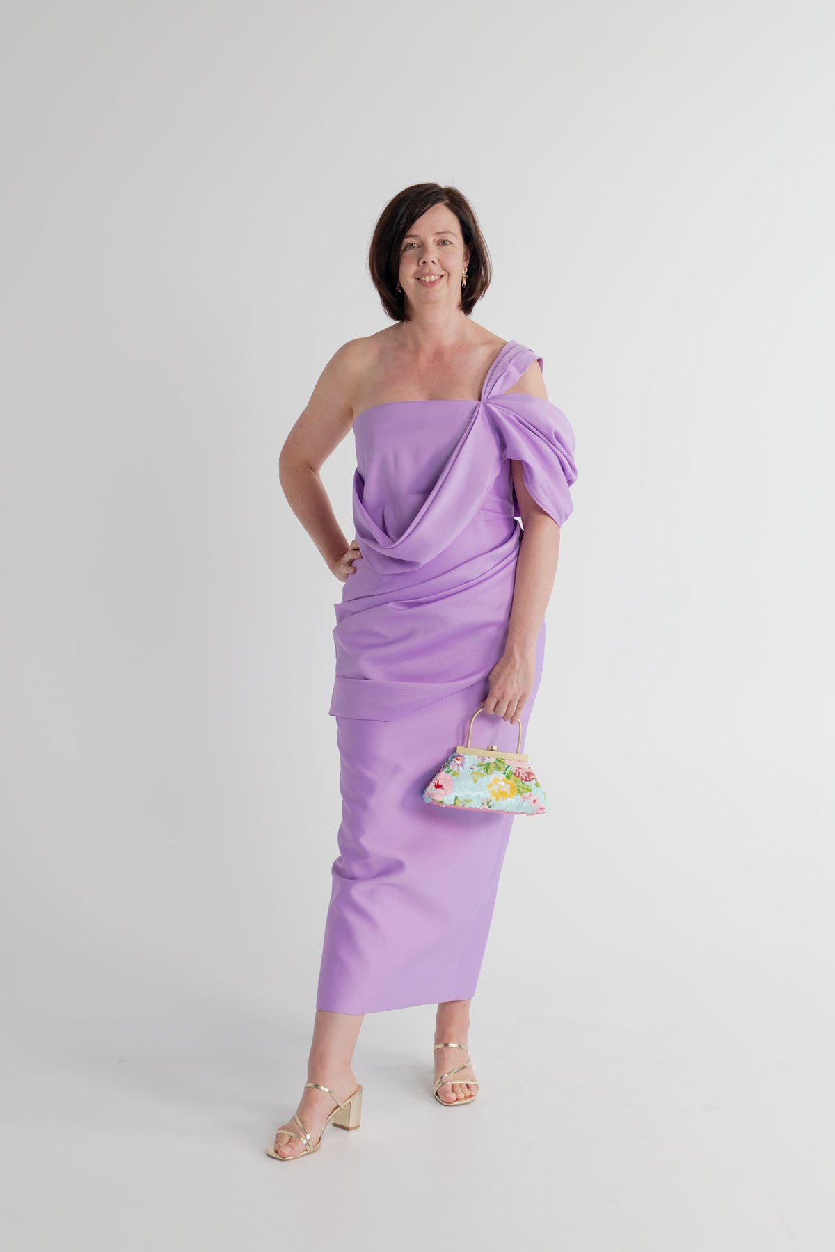 Eliya the Label Scarlett lilac one-shoulder midi dress with sculptural draping, styled with the Olga Berg Audrey floral sequin top handle bag.
