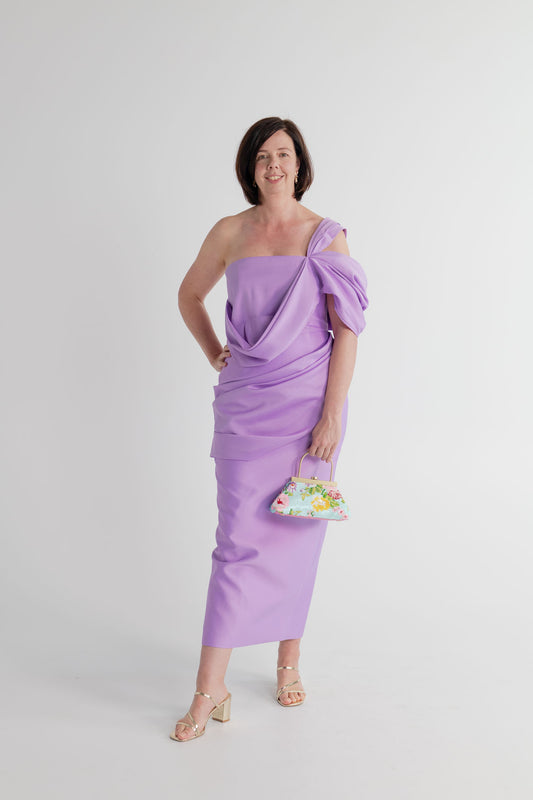 Eliya the Label Scarlett lilac one-shoulder midi dress with sculptural draping, styled with the Olga Berg Audrey floral sequin top handle bag.
