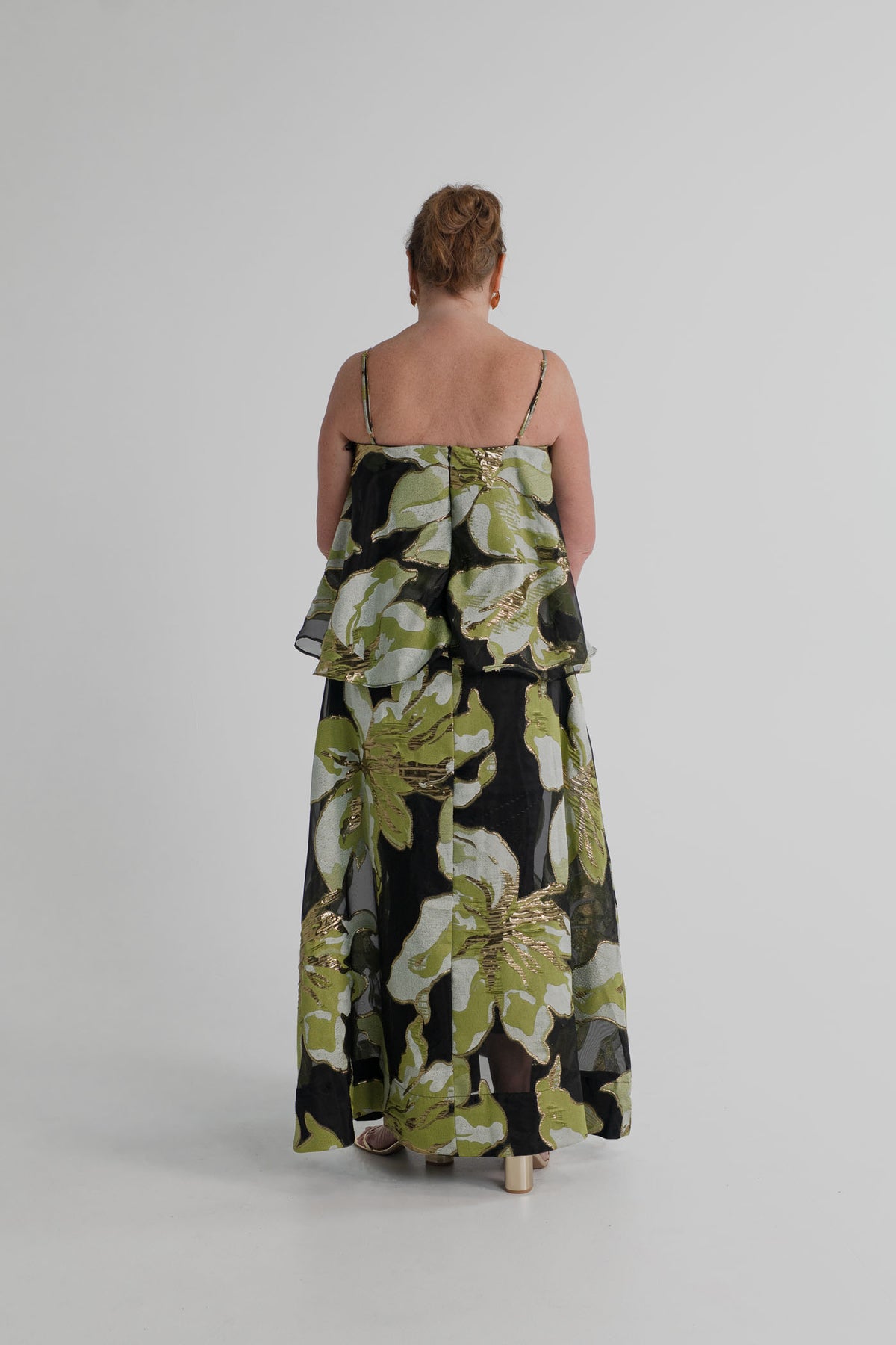 Back view of the Elliatt Elysia Tiered Gown showing the thin straps, layered bodice and full-length metallic floral skirt.
