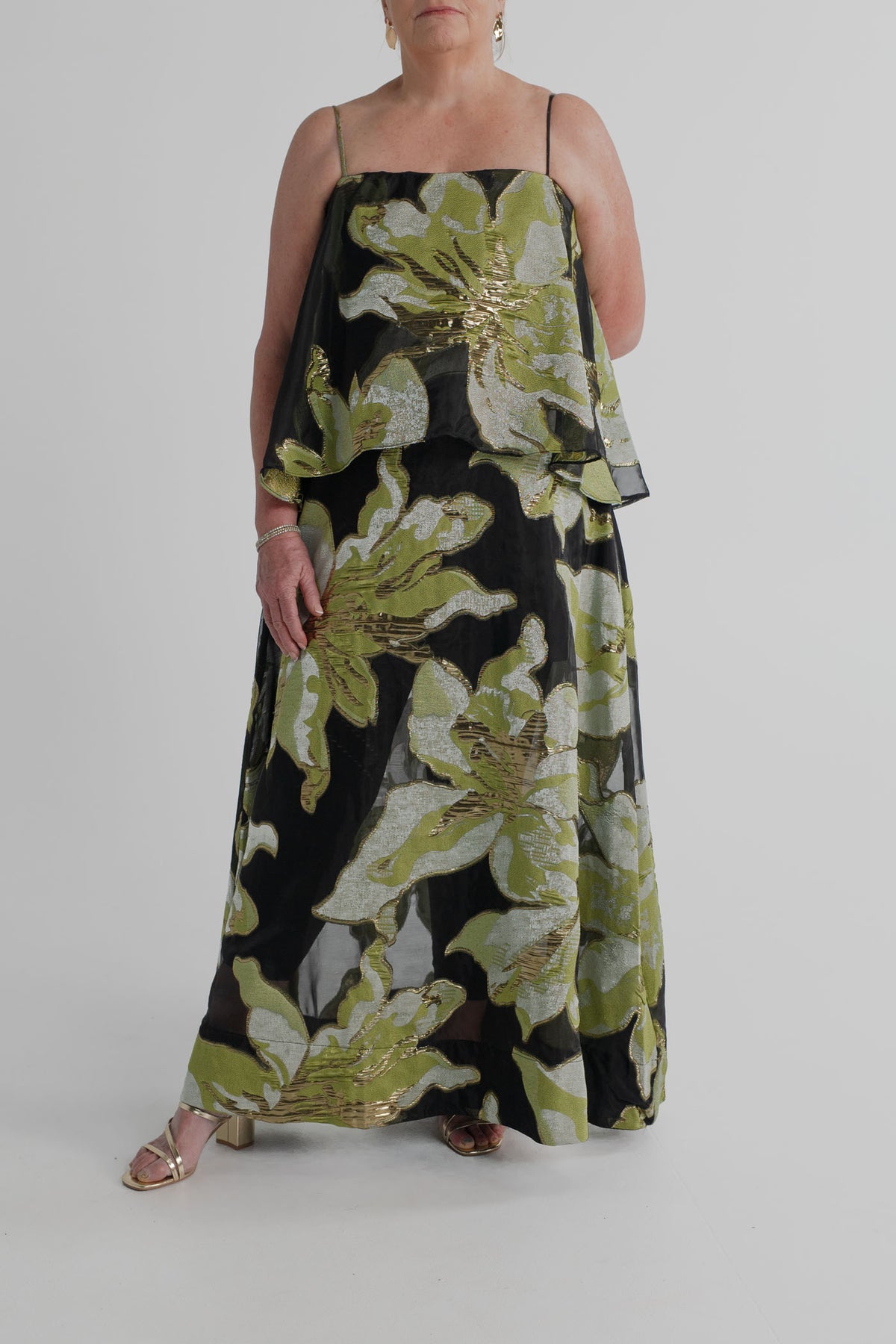 Front detail of the Elliatt Elysia Tiered Gown showing the flowing tiered overlay and metallic green, silver and gold floral jacquard on a sheer black base.
