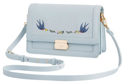 Angled view of Fable England pale blue Blue Bird embroidered foldover bag showing the structured side profile and shoulder strap. 
