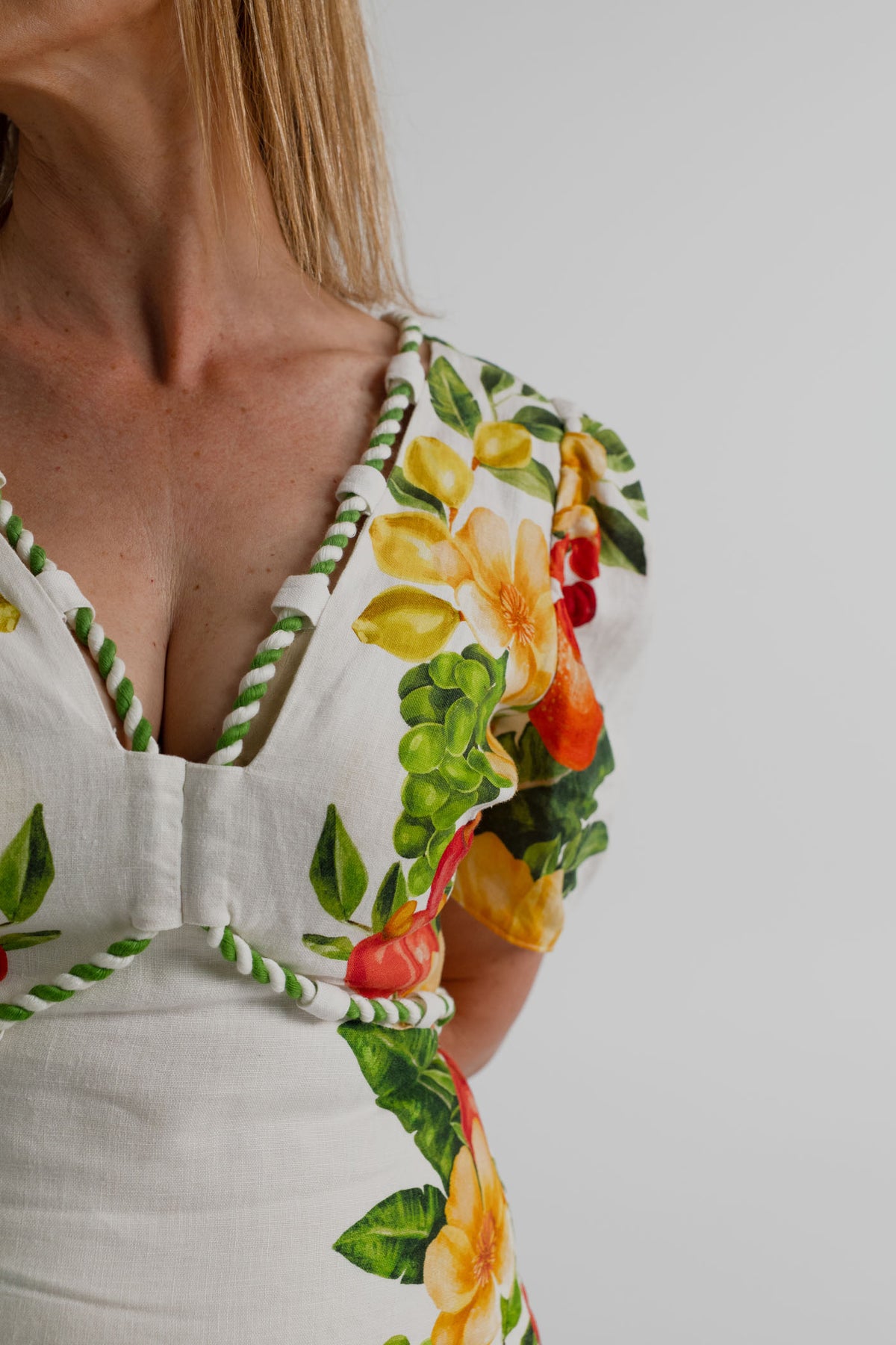 Close-up of the Farm Rio Picnic Flowers Off-White Maxi showing the deep V neckline, green-and-white twisted piping, puff sleeve and tropical print detail.
