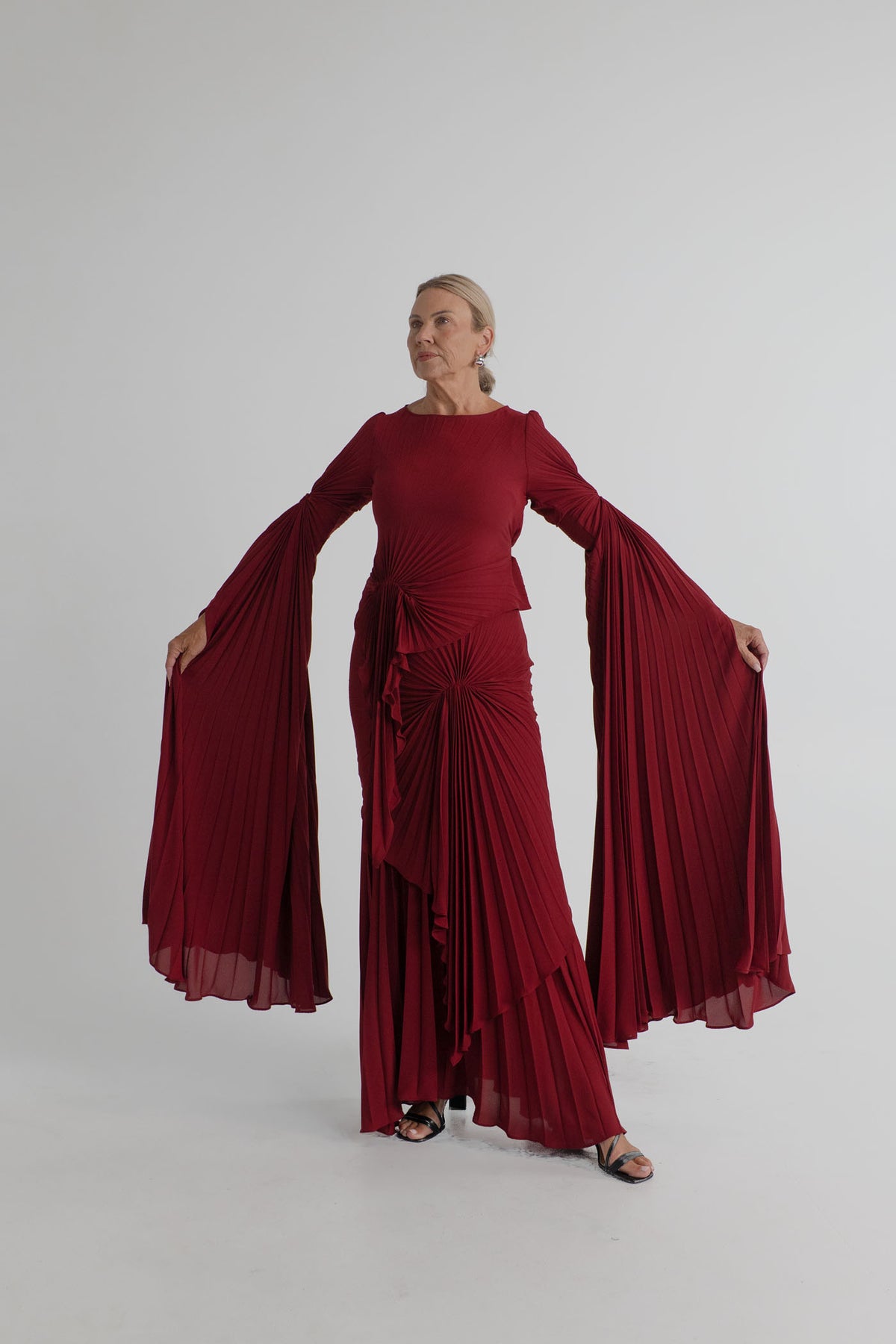 Georgia Hardinge Waterfall merlot pleated gown with dramatic draped sleeves, sculptural waterfall panels and floor-length silhouette.
