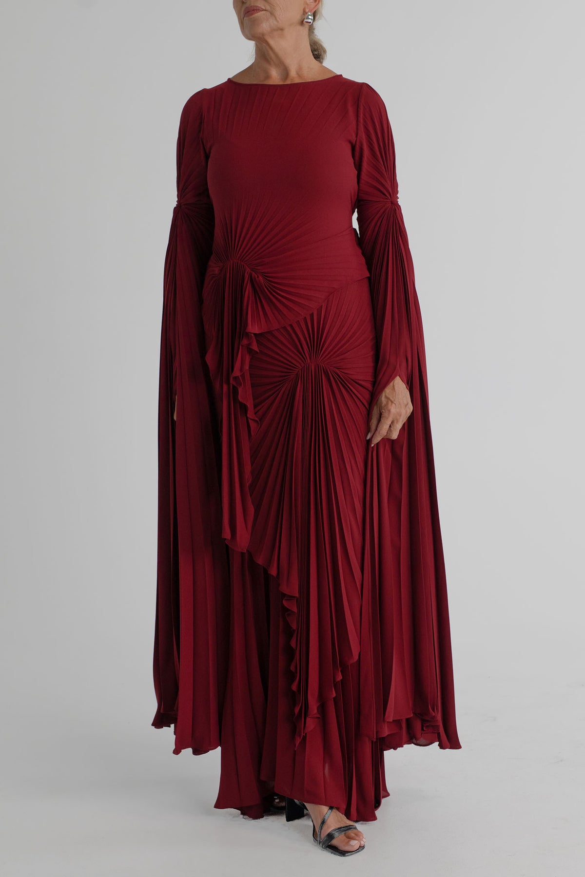 Georgia Hardinge Waterfall merlot pleated maxi gown with long draped sleeves, gathered waist and flowing full-length skirt.
