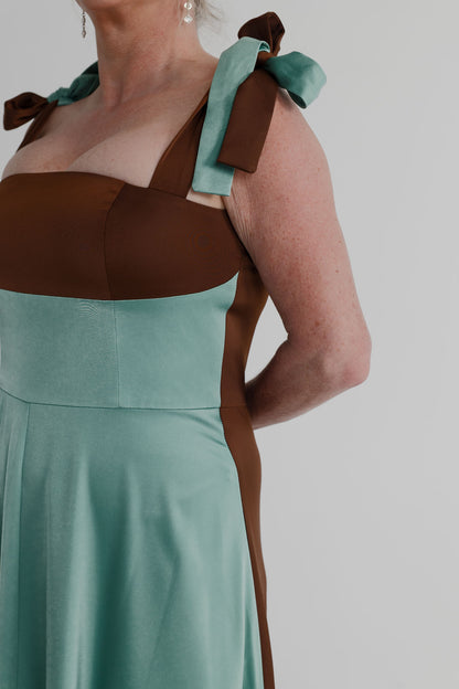 Close-up of the IQ Collection Carmen Midi showing the aqua and chocolate colour-blocked bodice, square neckline and contrasting shoulder ties.
