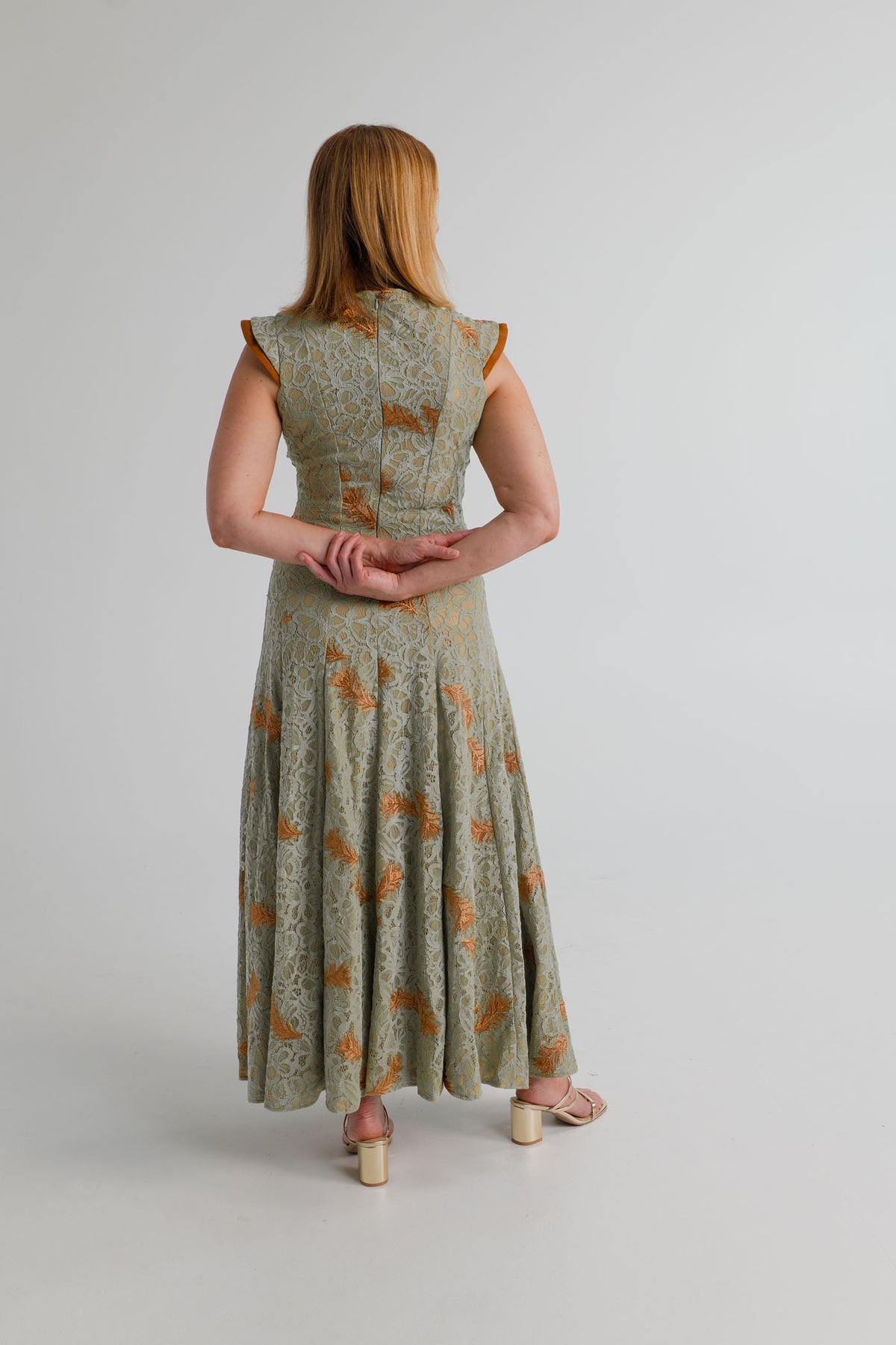 Back view of the IQ Collection Rose Maxi in sage lace, showing the fitted bodice, structured shoulders and flowing full-length skirt.
