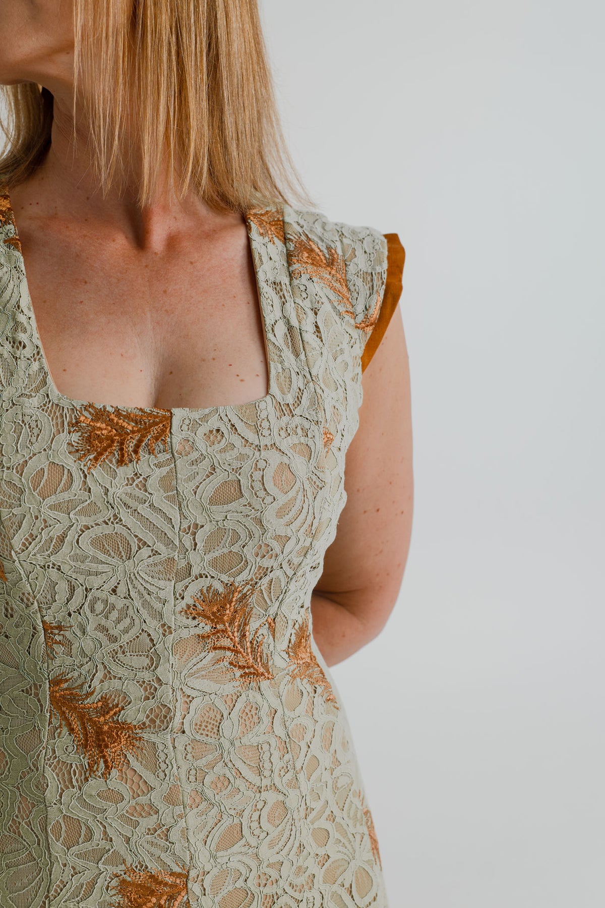 Close-up of the IQ Collection Rose Maxi showing the square neckline, sage floral lace and copper embroidered detailing.
