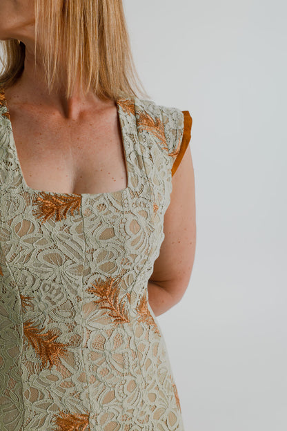 Close-up of the IQ Collection Rose Maxi showing the square neckline, sage floral lace and copper embroidered detailing.

