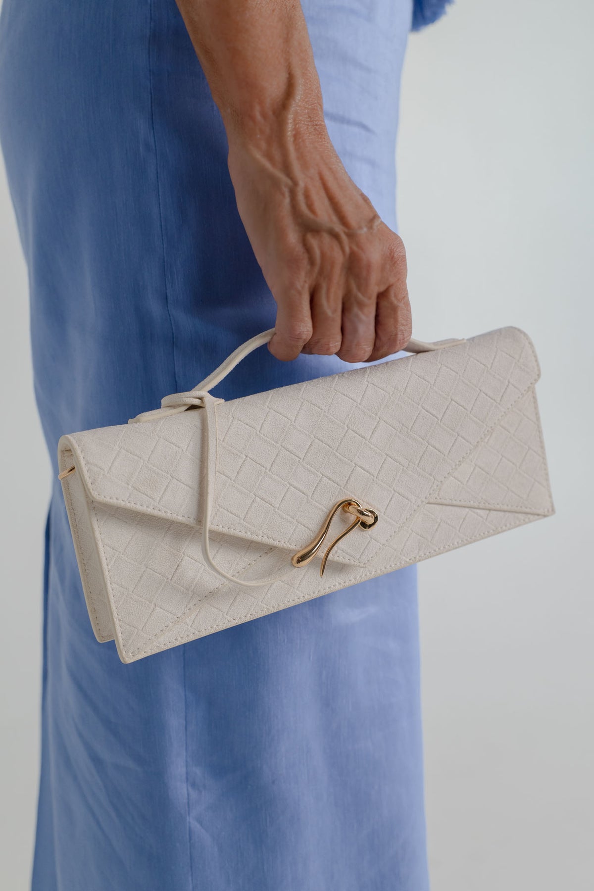 Close-up of the JW Pei Celeste cream woven top handle bag with gold-tone closure, styled against the Aje Kira blue midi dress.
