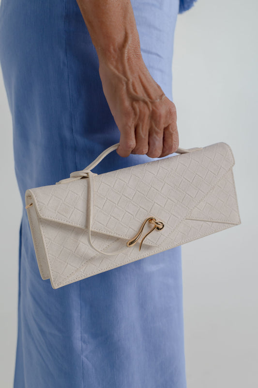 Close-up of the JW Pei Celeste cream woven top handle bag with gold-tone closure, styled against the Aje Kira blue midi dress.
