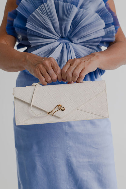 JW Pei Celeste cream woven top handle bag with gold-tone hardware, styled with the sculptural pleated bodice of the Aje Kira blue midi dress.
