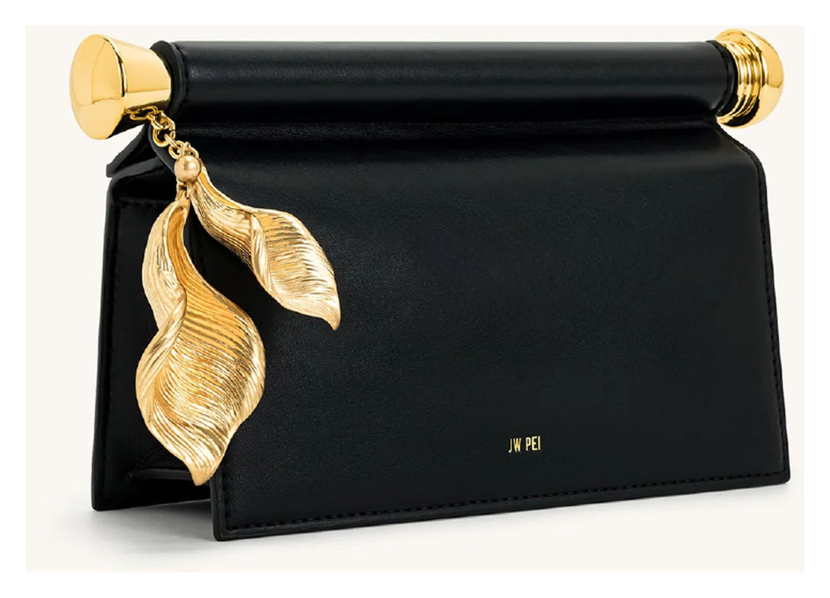 Angled side view of JW Pei Holly black embellished clutch with structured profile and gold-tone leaf pendant. 
