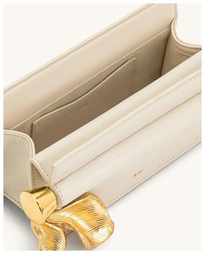 Open view of JW Pei Holly cream clutch showing the light interior and gold-tone leaf pendant detail. 
