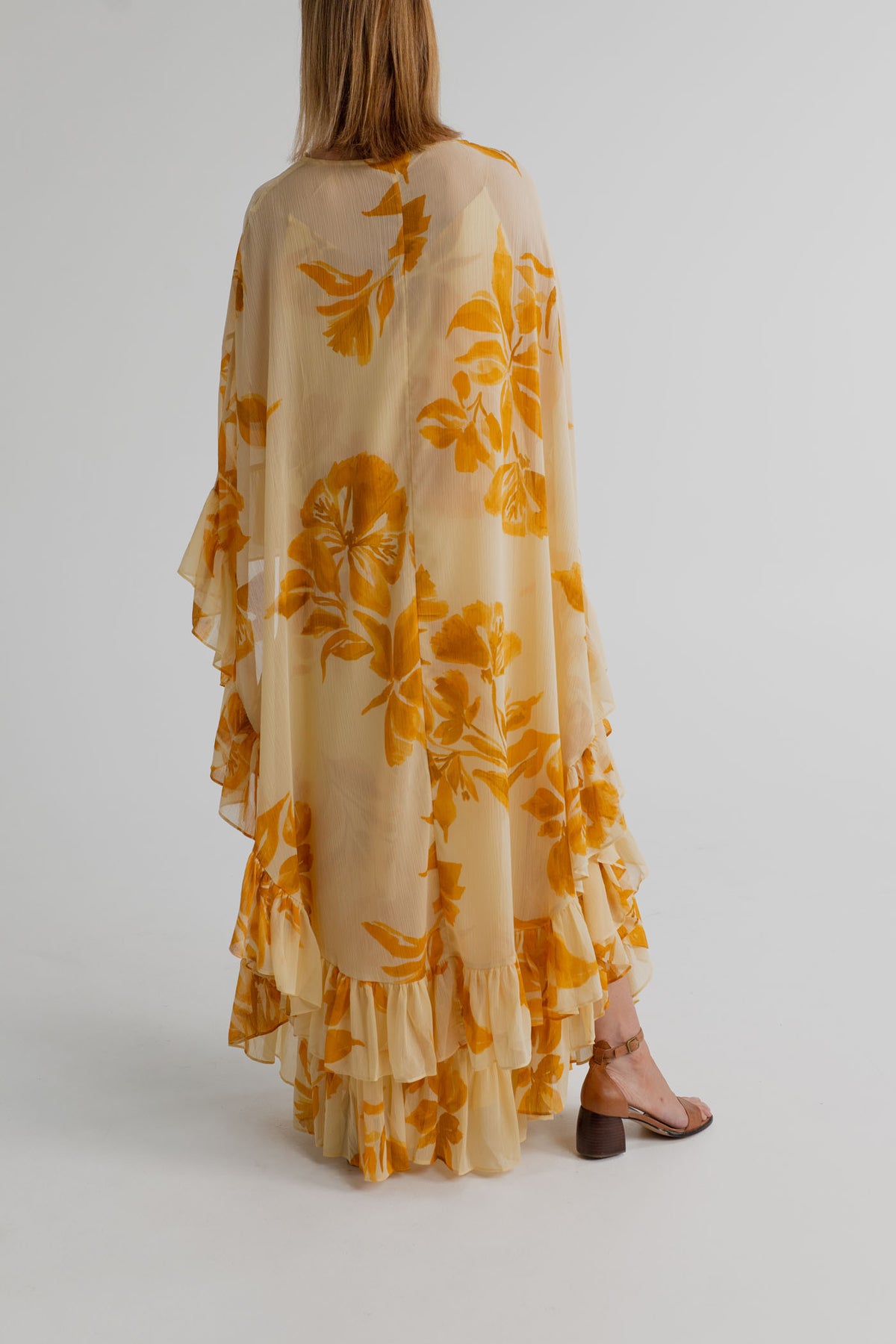 Back view of the Monsoon Joanna Ruffle Cape Maxi showing the sheer cream cape, mustard floral print and layered ruffle hem.
