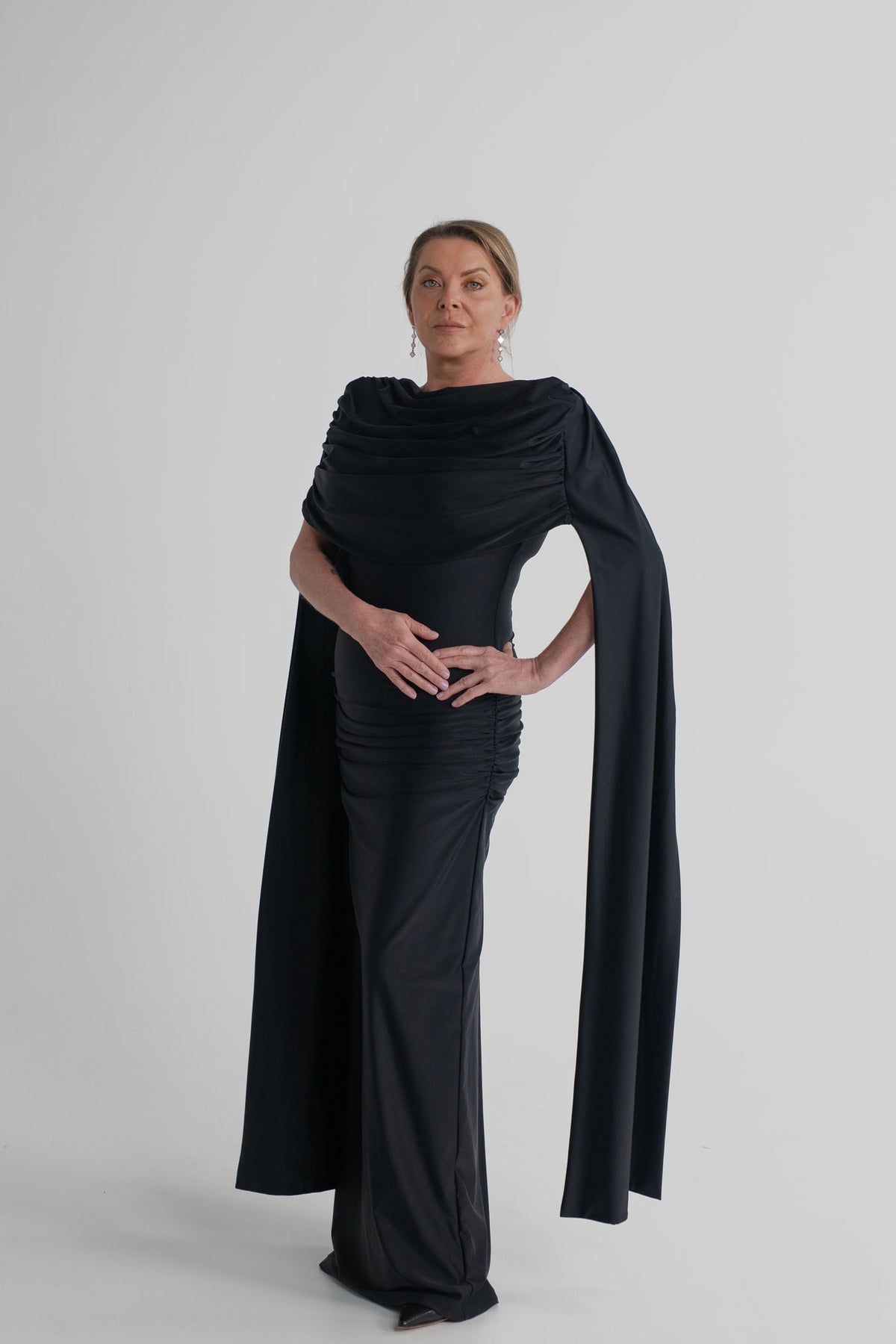 Mossman Reign black midi dress with softly draped off-shoulder neckline, dramatic cape sleeves and fitted column silhouette.
