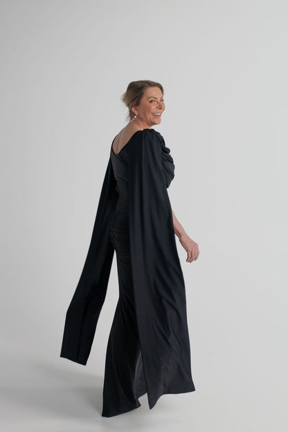 Side and back view of the Mossman Reign black midi dress showing the elongated cape sleeves, open back and fitted silhouette.
