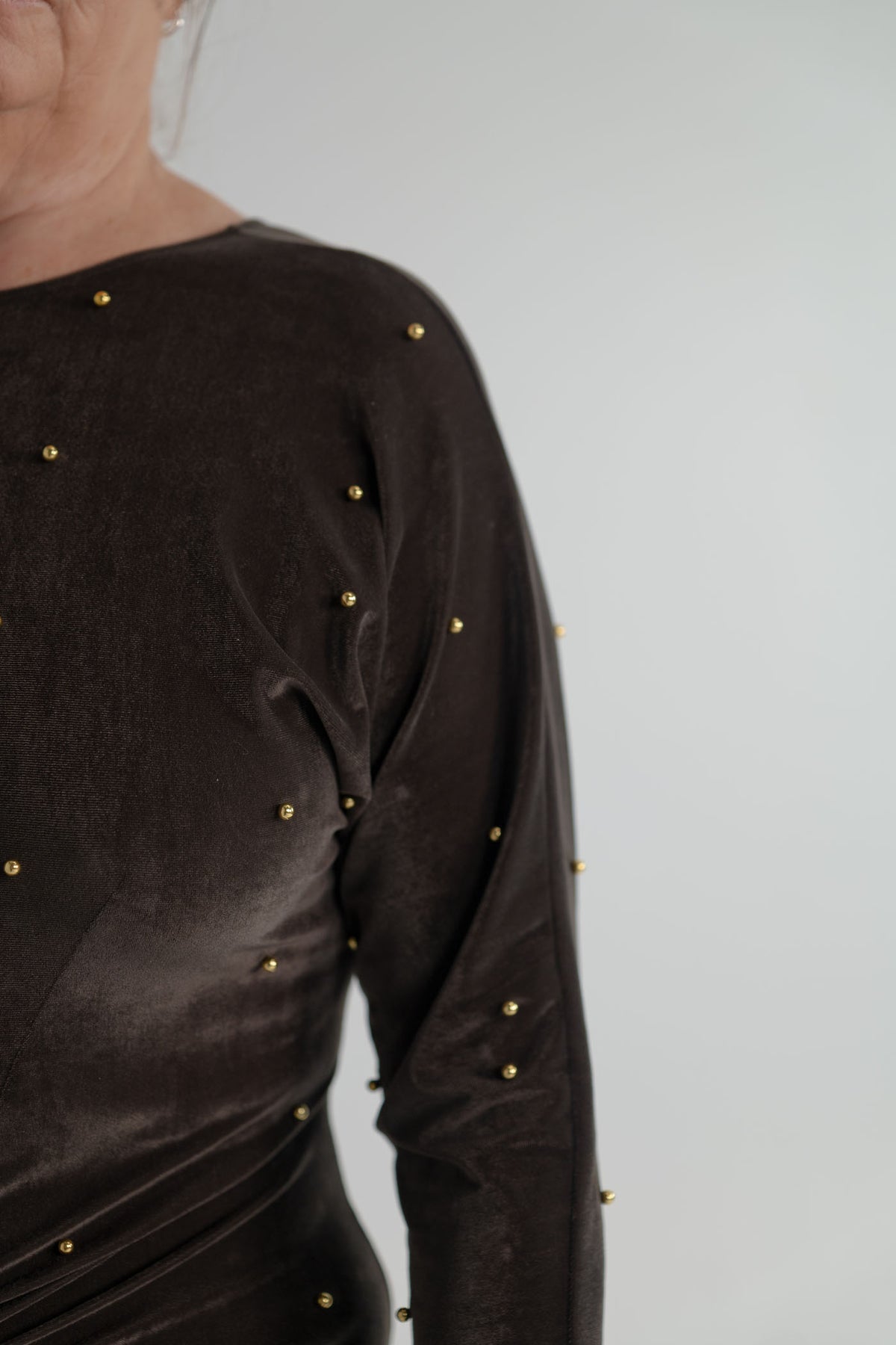 One Fell Swoop Lucent Iron Maiden dark bronze velour maxi dress with long sleeves, sculptural ruched waist and scattered gold pearl detailing.
