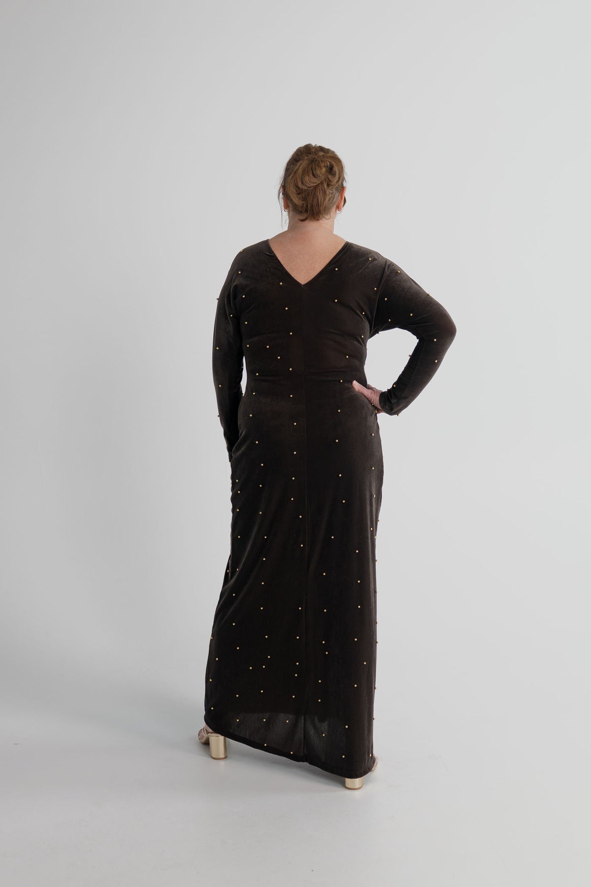 One Fell Swoop Lucent Iron Maiden dark bronze velour maxi dress with gold pearl embellishment and sculptural gathering through the waist.
