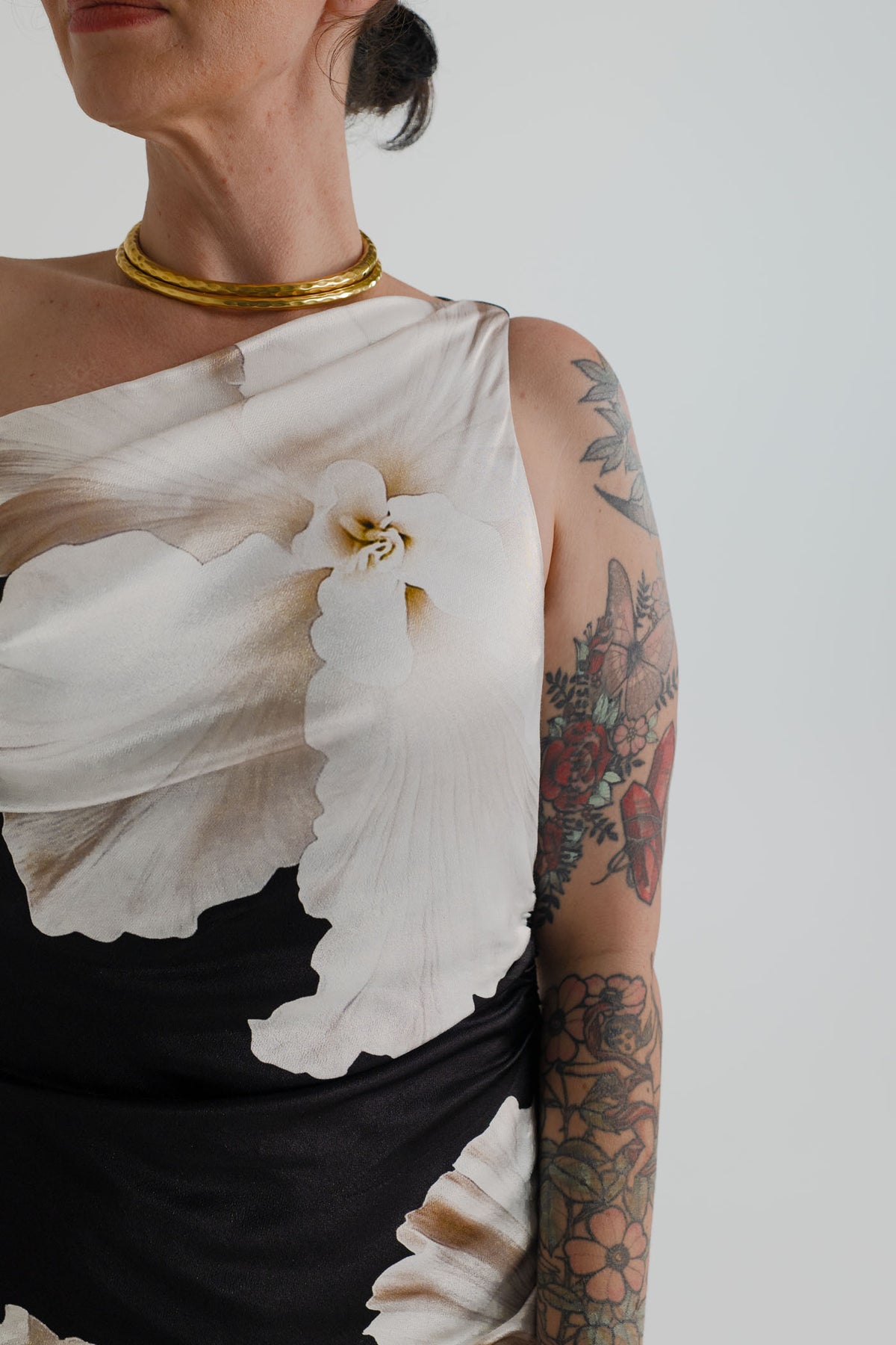 Close-up of the Pasduchas Finley Midnight Bloom showing its asymmetric one-shoulder neckline and oversized ivory floral print.
