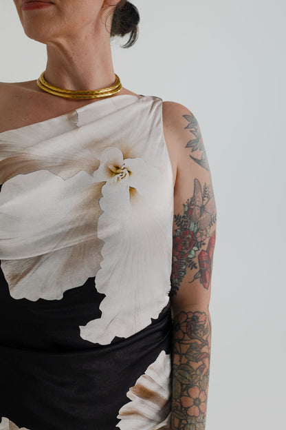 Close-up of the Pasduchas Finley Midnight Bloom showing its asymmetric one-shoulder neckline and oversized ivory floral print.
