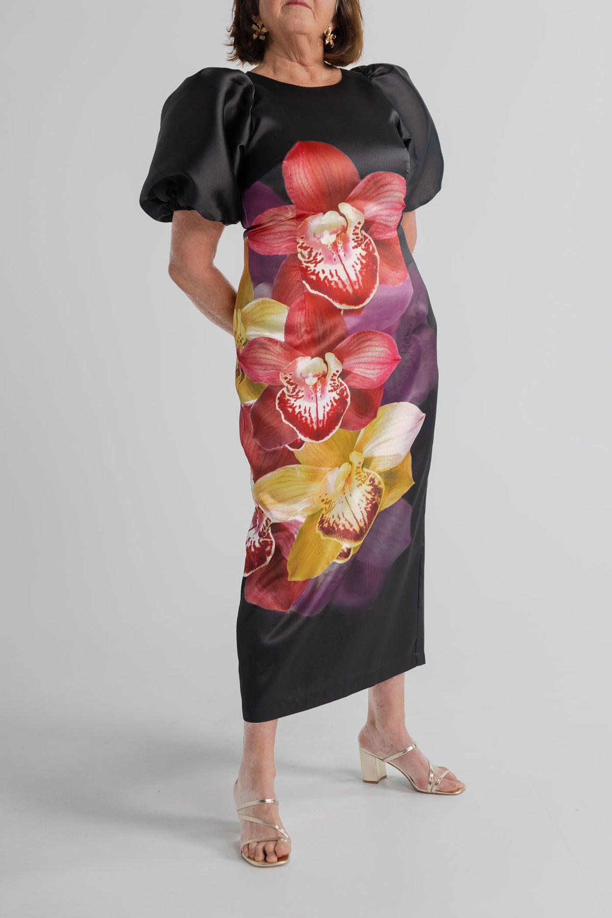 Pasduchas Nova Black Orchid midi dress with statement orchid print, short puff sleeves and streamlined fitted shape.
