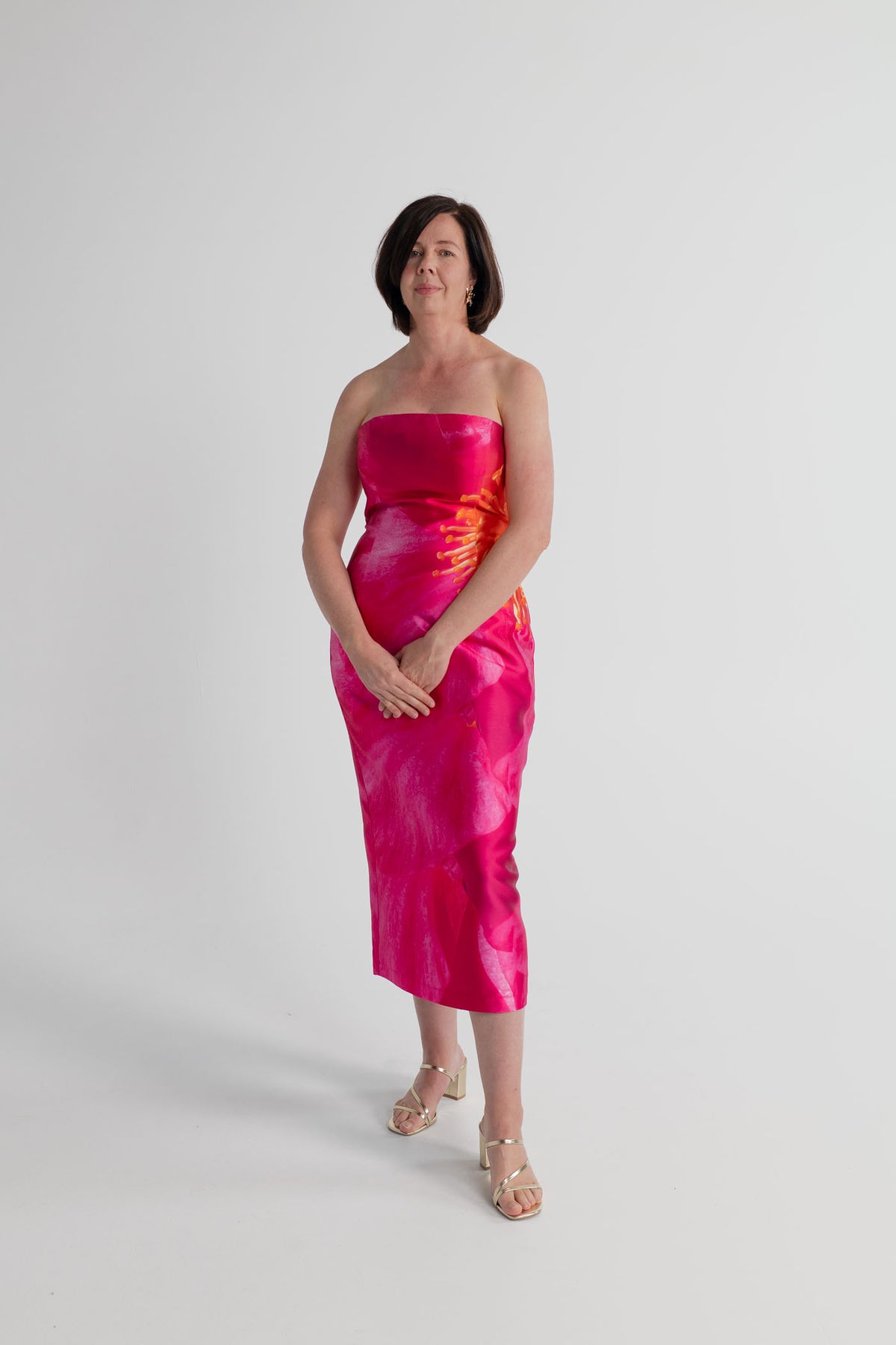 Pasduchas Thea Camellia Pink strapless midi dress with oversized orange floral placement print and structured fitted silhouette.
