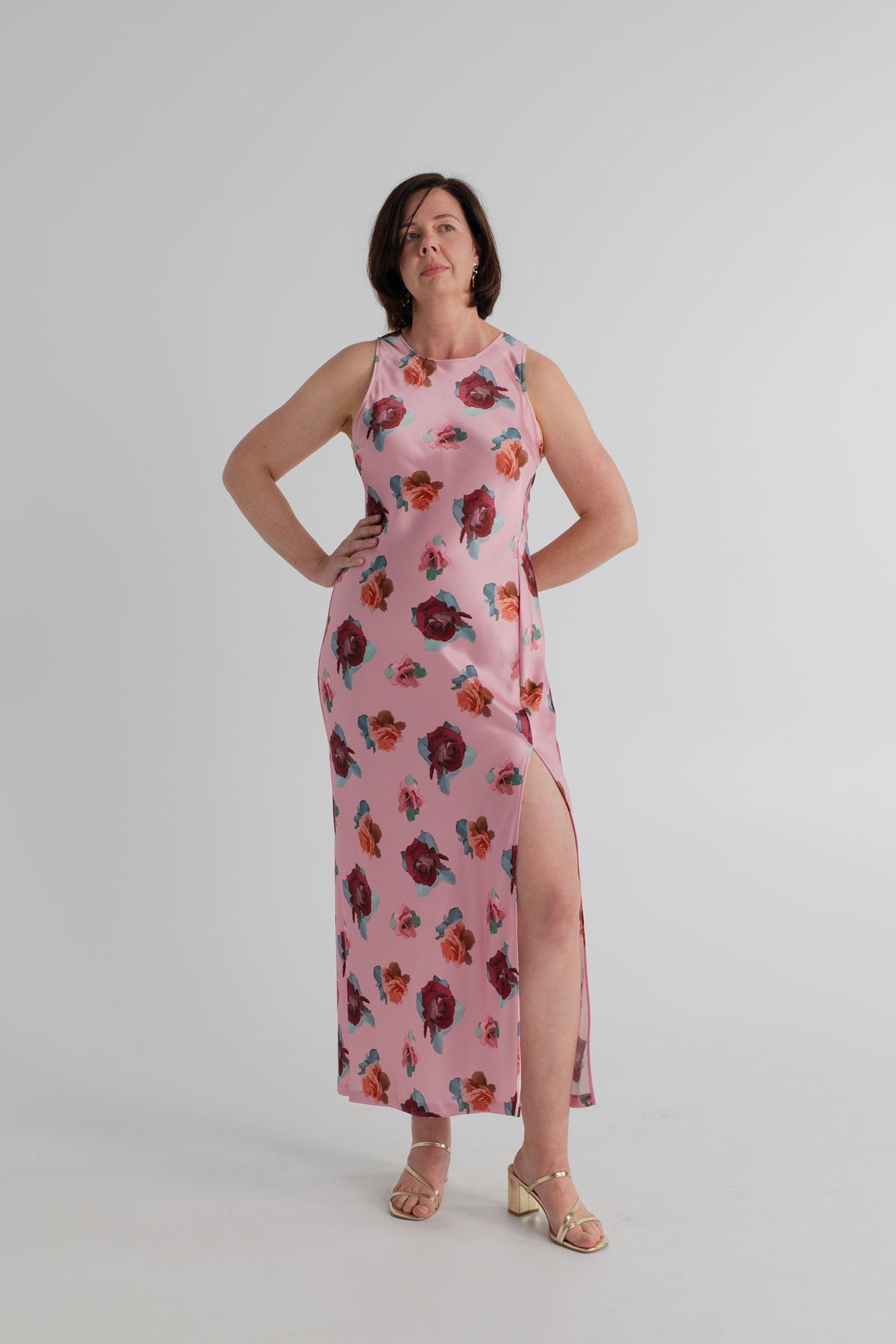 SABA Bettina Maxi Dress in pink satin with scattered floral print, sleeveless high neckline, fitted column silhouette and thigh-high side split. 
