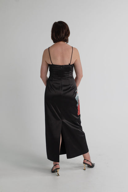 Back view of the Saba Corsage Midi Dress showing fine shoulder straps, fitted black satin silhouette, centre-back zip and rear split.

