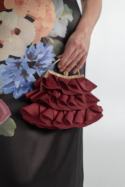 Close-up of the Saba Corsage Midi Dress floral print styled with the Verano Hill Colette Ruffle bag in deep burgundy.
