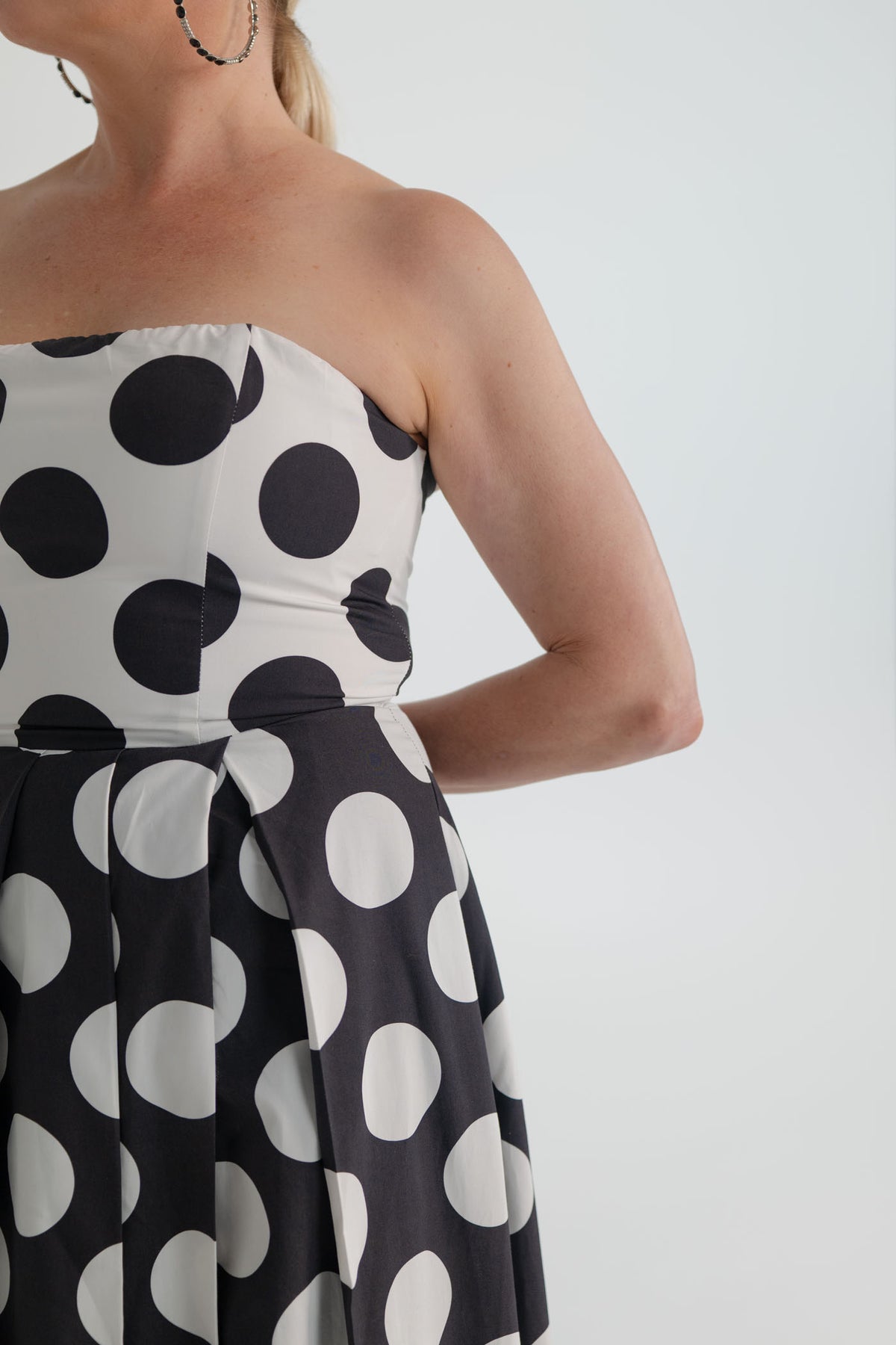 Close-up of the Sonya Moda Milano Gown showing the structured strapless white bodice with oversized black polka dots and contrasting black-and-white skirt. 
