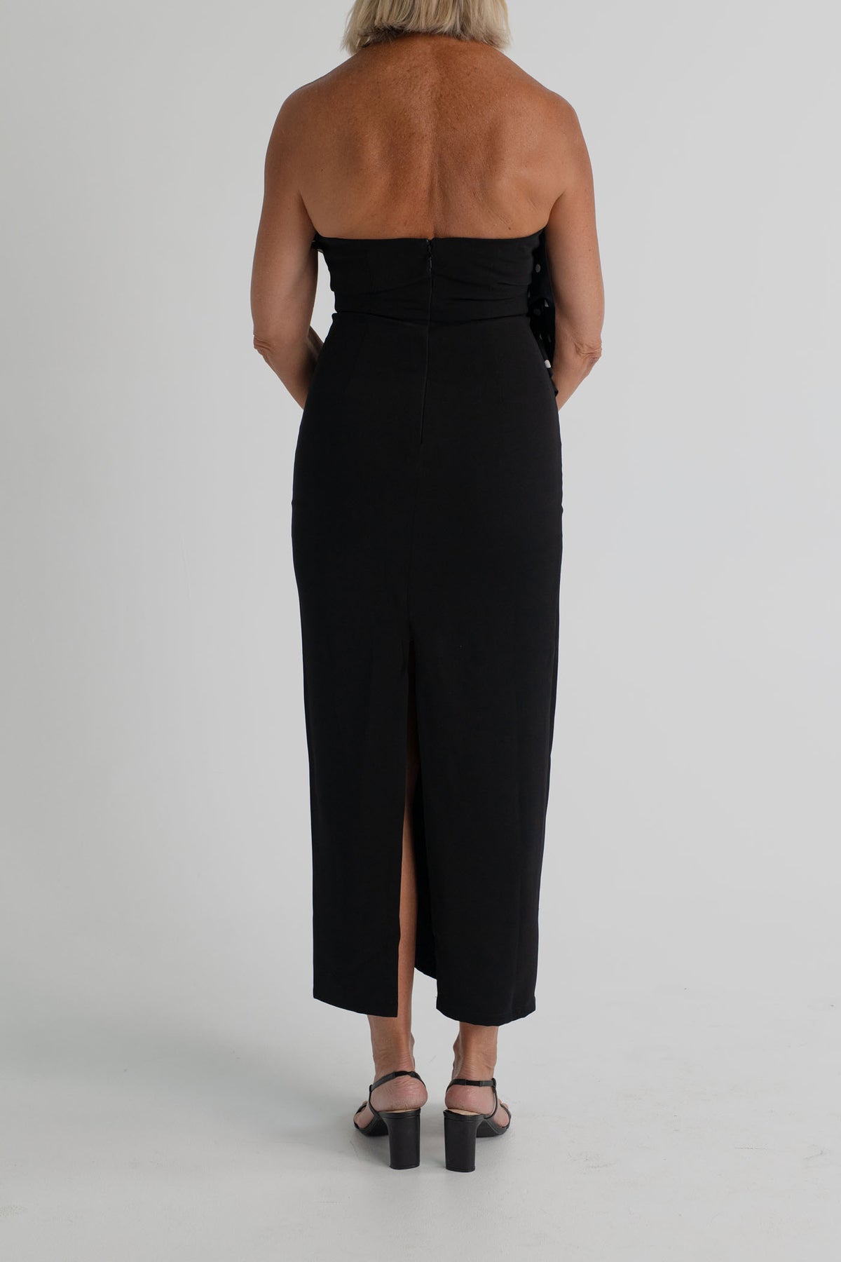 Back view of the Sonya Moda Palermo Dress showing the strapless fitted black silhouette, centre-back zip and back split. 
