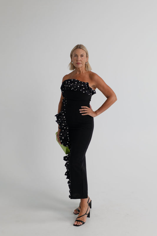 Sonya Moda Palermo Dress in black with a strapless fitted silhouette and black-and-white polka-dot ruffle detail across the neckline and down the side. 

