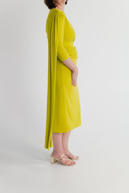 Side view of the chartreuse Strena Barbara Midi Dress highlighting the long asymmetric shoulder drape, fitted waist and midi-length silhouette.
