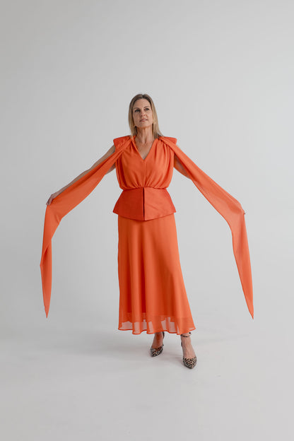 Strena Diana Midi Dress in orange, shown full length from the front with its long scarf ties extended from the shoulders and a softly draped midi skirt.
