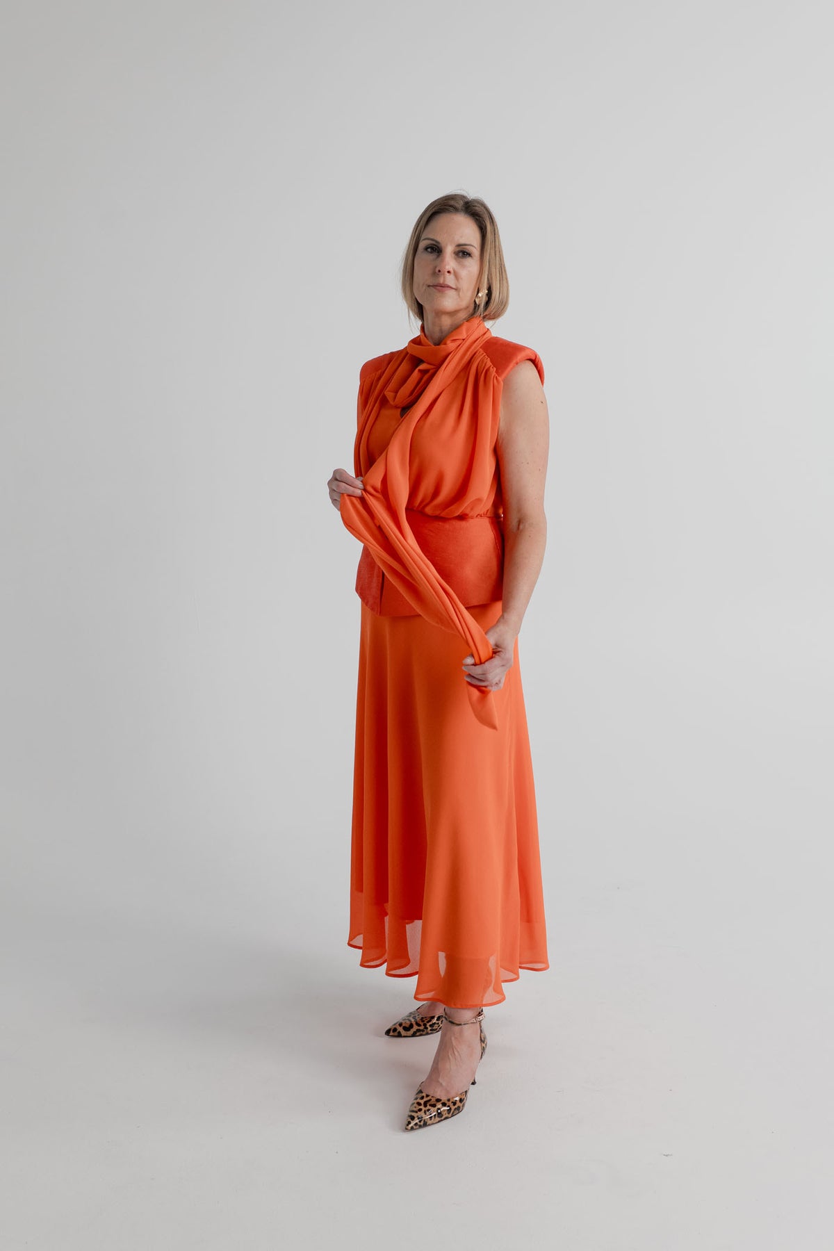 Strena Diana Midi Dress in orange with the long shoulder scarf wrapped loosely around the neckline to show an alternate styling option.
