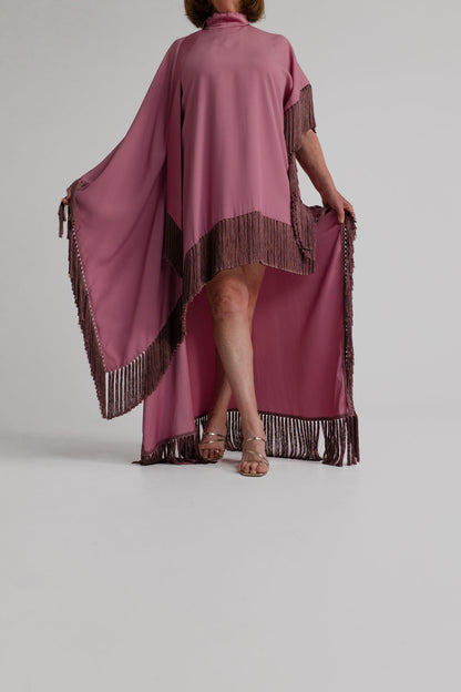 Front movement view of the Taller Marmo Asymmetrical Fringed Satin Kaftan highlighting the asymmetric hem, cape drape and long fringe detailing.
