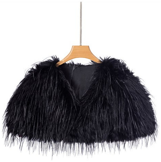 The Two Mrs Grenvilles black faux fur shrug on a hanger showing the cropped cape-style shape, open front and long-pile faux fur finish. 
