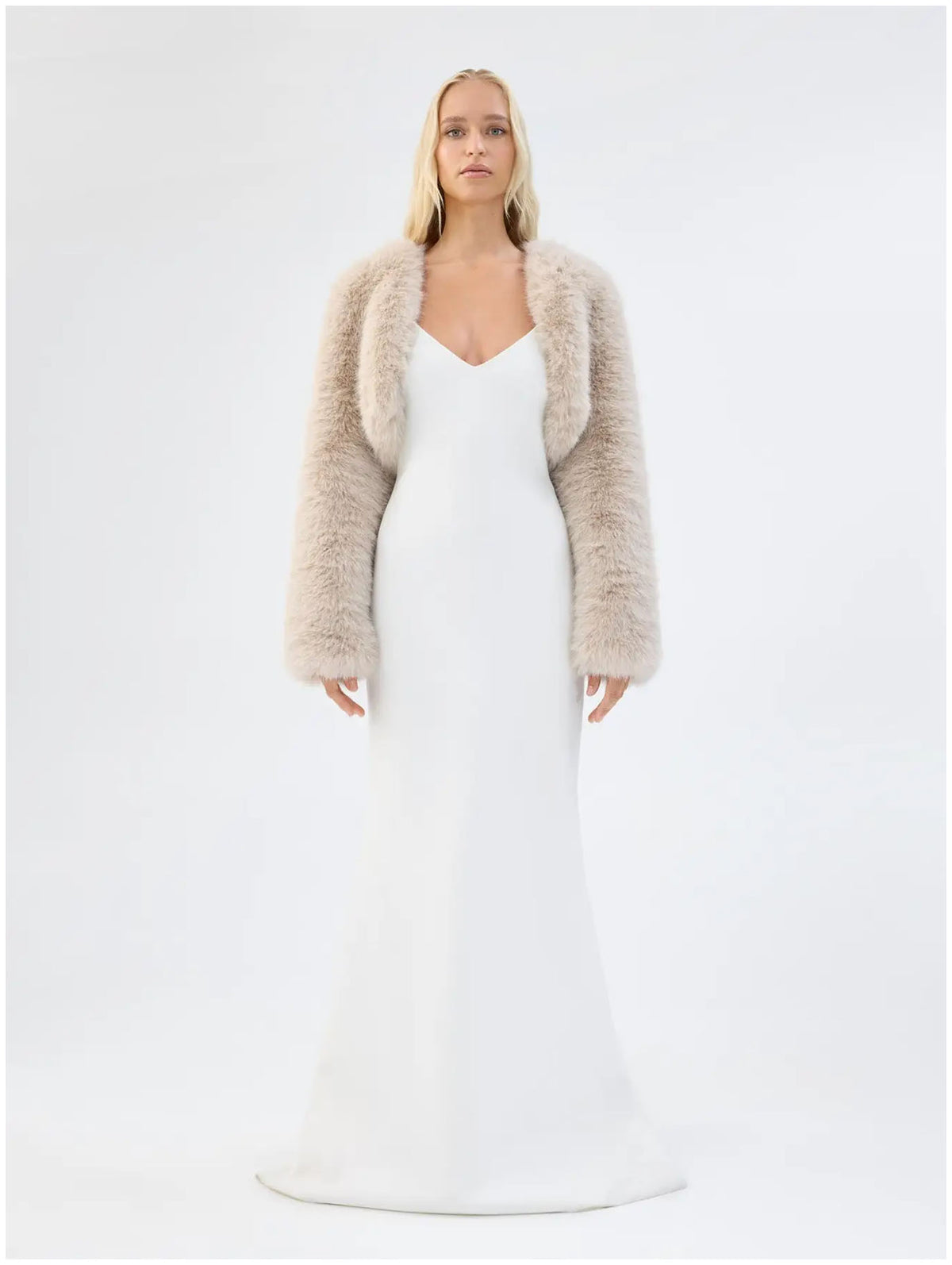 Model wearing Unreal Fur Empress almond faux fur jacket with long sleeves and cropped bolero silhouette, front view. 
