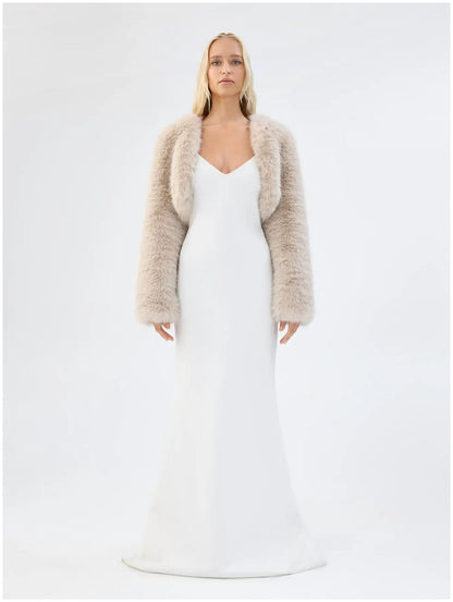 Model wearing Unreal Fur Empress almond faux fur jacket with long sleeves and cropped bolero silhouette, front view. 
