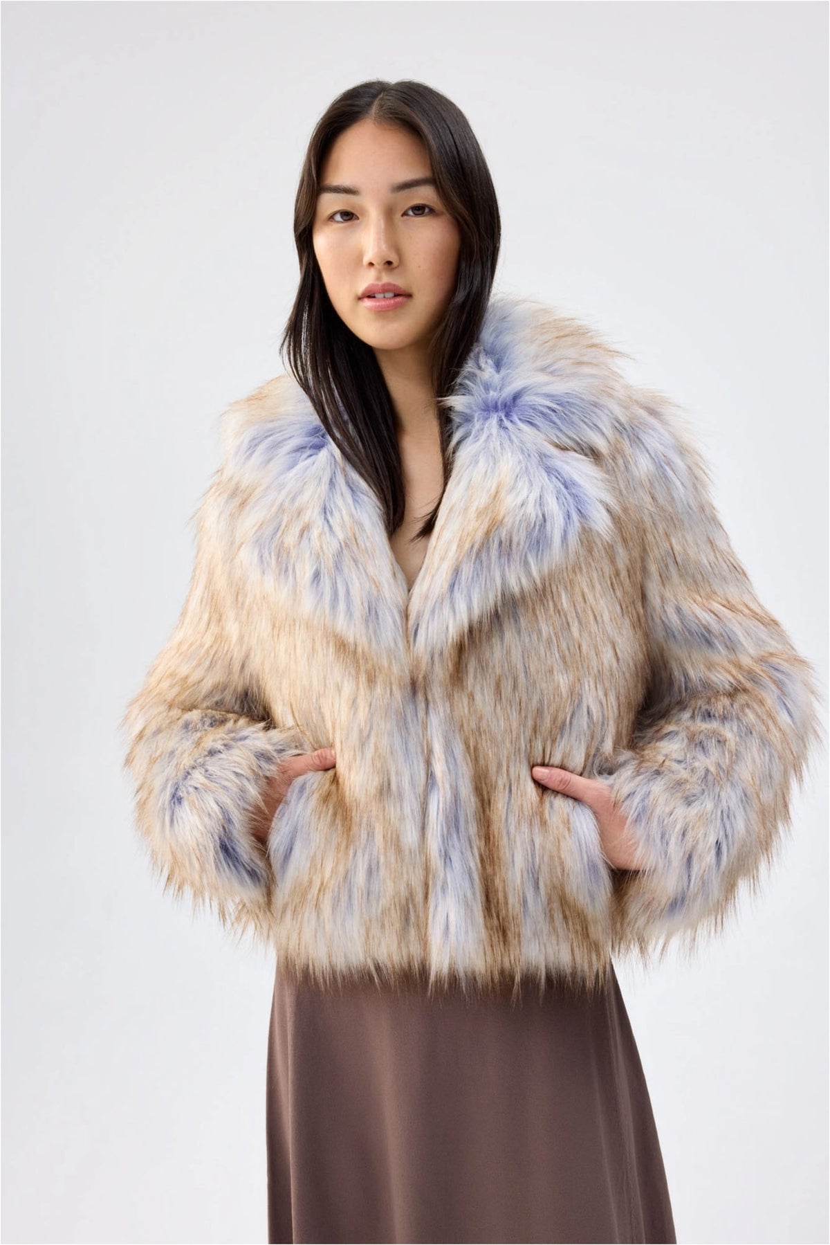 Close-up of Unreal Fur Harmony Purple Coyote faux fur jacket showing the side pockets, plush collar and multitone cream, tan and soft purple faux fur texture. 

