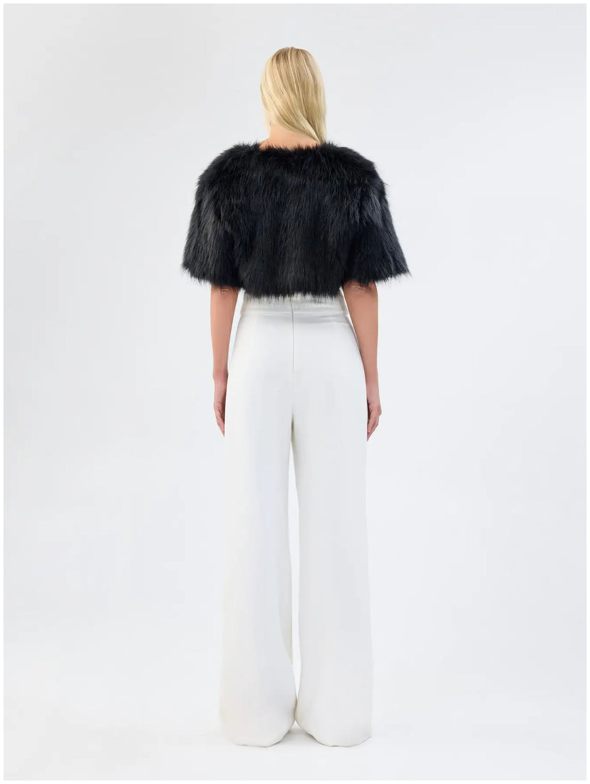Back view of Unreal Fur Love a Fur black faux fur bolero showing the cropped length, plush texture and short sleeves. 
